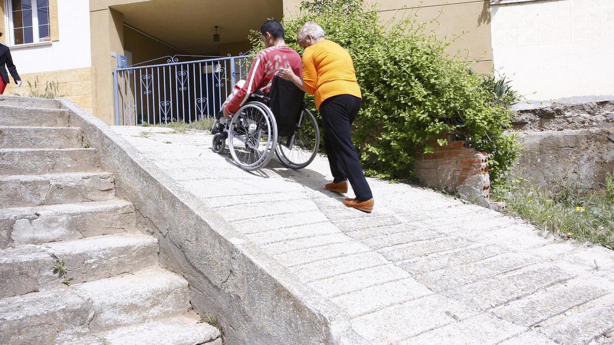 Una persona empuja una silla de ruedas.