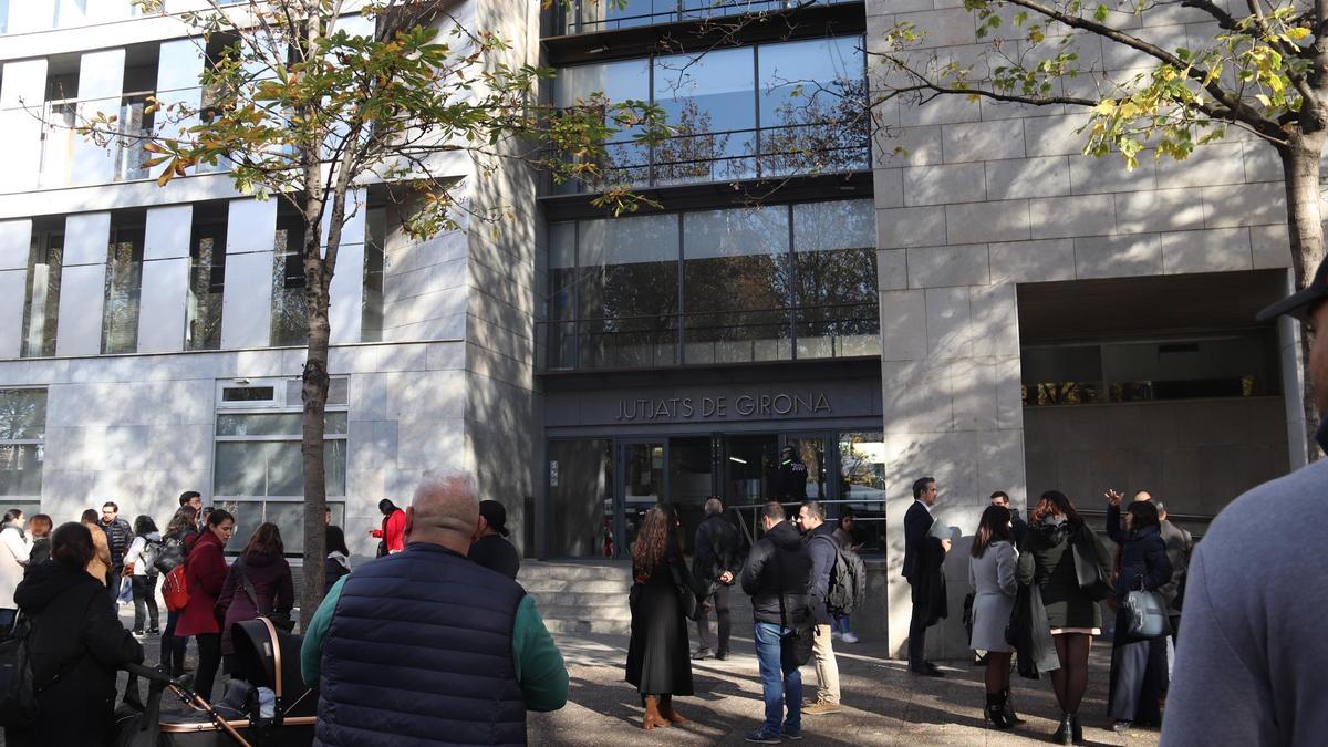 Diverses persones s'esperen a fora dels Jutjats de Girona mentre els Bombers treballen en l'avís per una columna de fum
