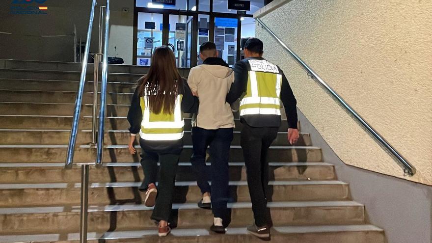 El fugitivo, de espaldas y junto a dos agentes de la Policía Nacional, entrando en dependencias policiales.