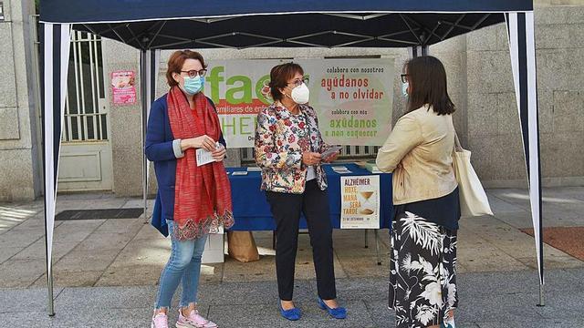 Noa Gallego y Quina Pérez, de la entidad Afaor, informan sobre el alzhéimer a una transeúnte. | // IÑAKI OSORIO