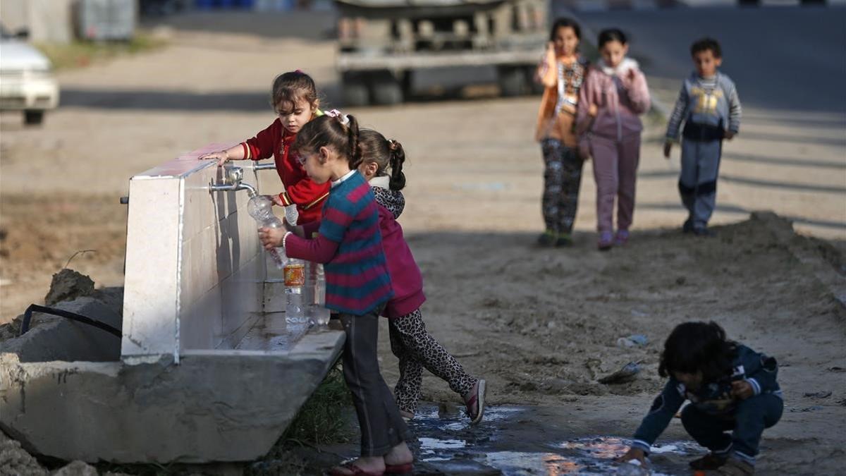 Niños palestinos llenan botellas de agua en una fuente en el campo de refugiados de Khan Yunis, al sur de Gaza, el 11 de abril del 2020
