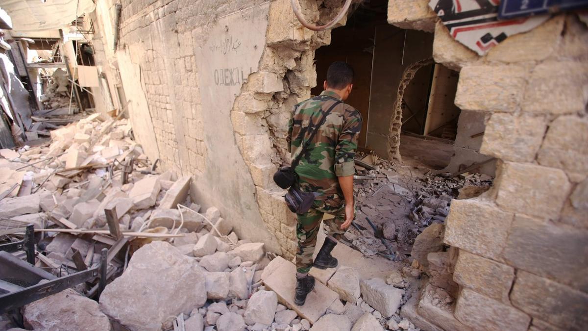 Un soldado del Ejército sirio inspecciona un edificio dañado en Alepo.