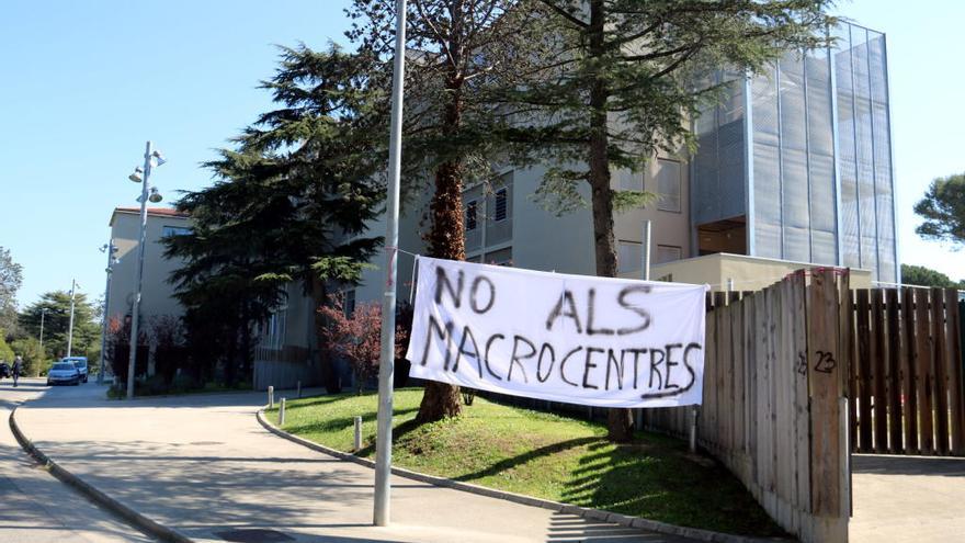 Imatge exterior del centre de la Misericòrdia de Girona -on anirà el nou centre d&#039;acollida- amb una pancarta en contra del &quot;macrocentre&quot;