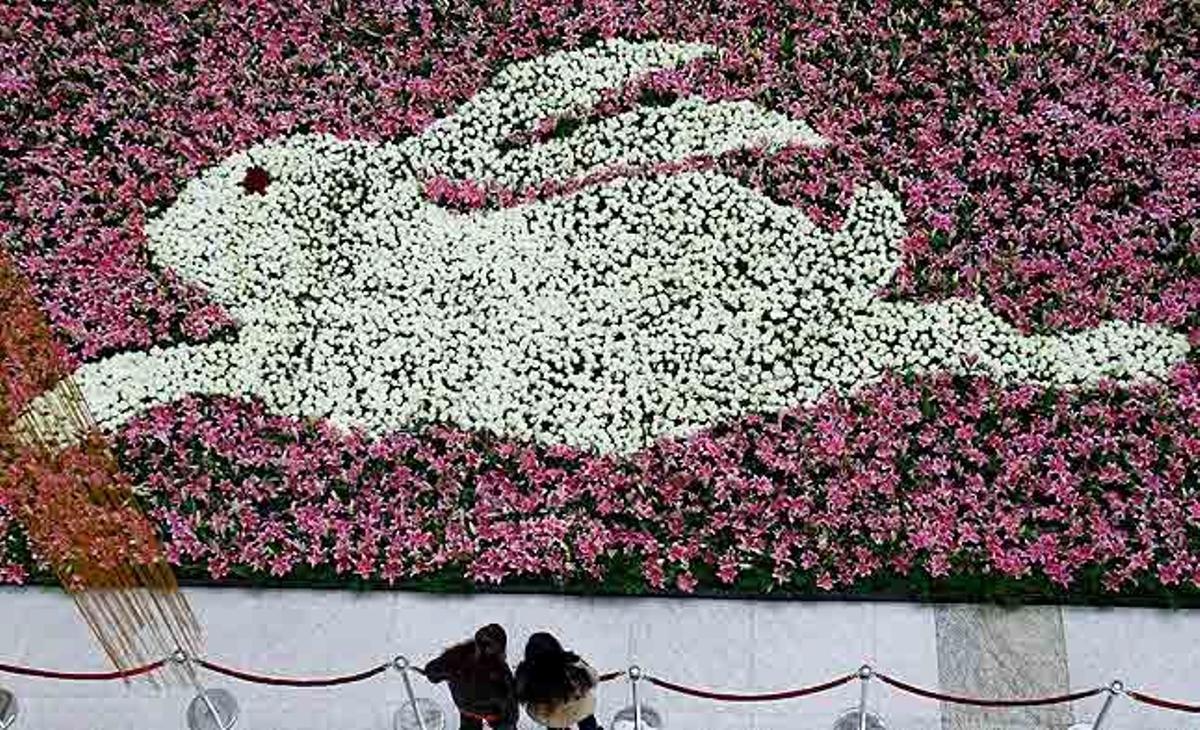 Dues persones observen una decoració floral amb forma de conill, feta de roses vermelles i liles, amb motiu de l’inici de l’Any del conill per als xinesos, a Nanjing.
