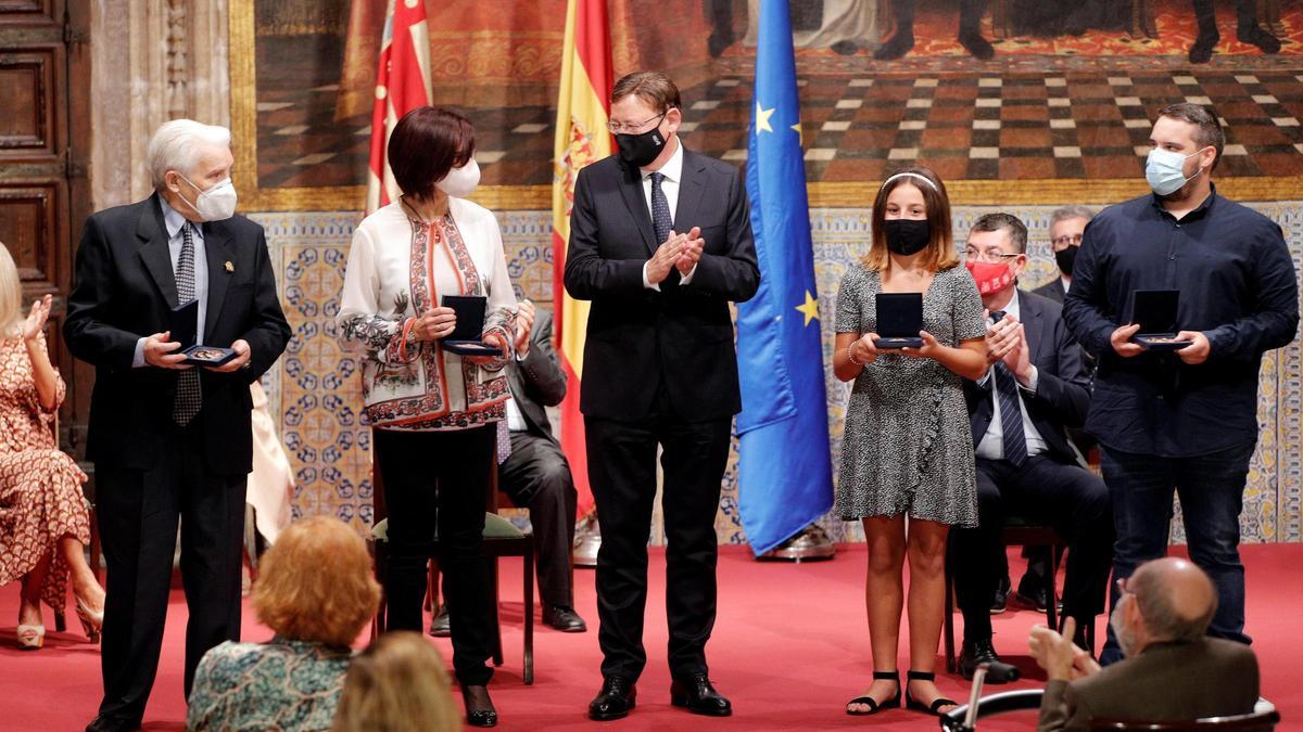 El president de la Generalitat, Ximo Puig (c), entrega la Alta Distinción al Pueblo Valenciano que recogen en el Palau de la Generalitat en nombre de todos los valencianos y valencianas, Rafael López (i), Losar Bretó (2ª i), Tania Ferrer (2ª d), y Vicente Dalmau