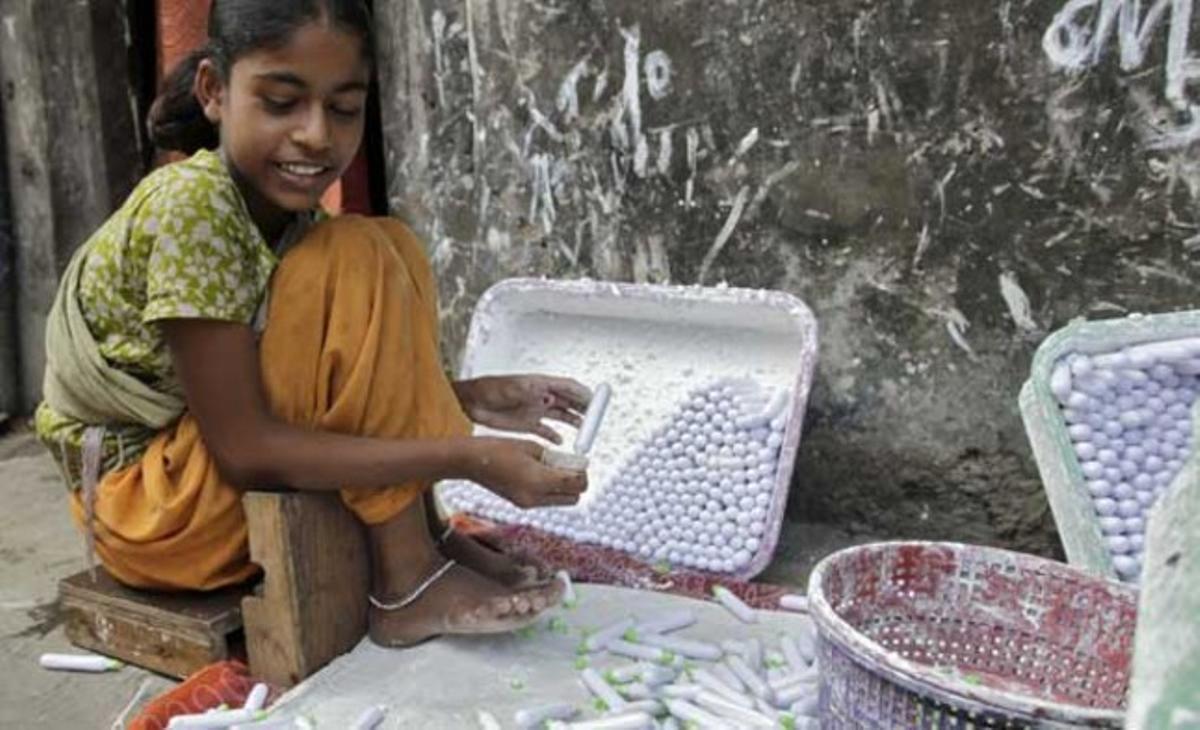 Una nena empaqueta tubs de llima a la porta de casa seva, en un barri pobre de Bombai (Índia). La noia afirma que guanya al voltant d’un euro al dia per empaquetar gairebé 4.000 tubs de pasta de llima. Aquesta es barreja amb el tabac masticable per donar-li un toc més saborós.