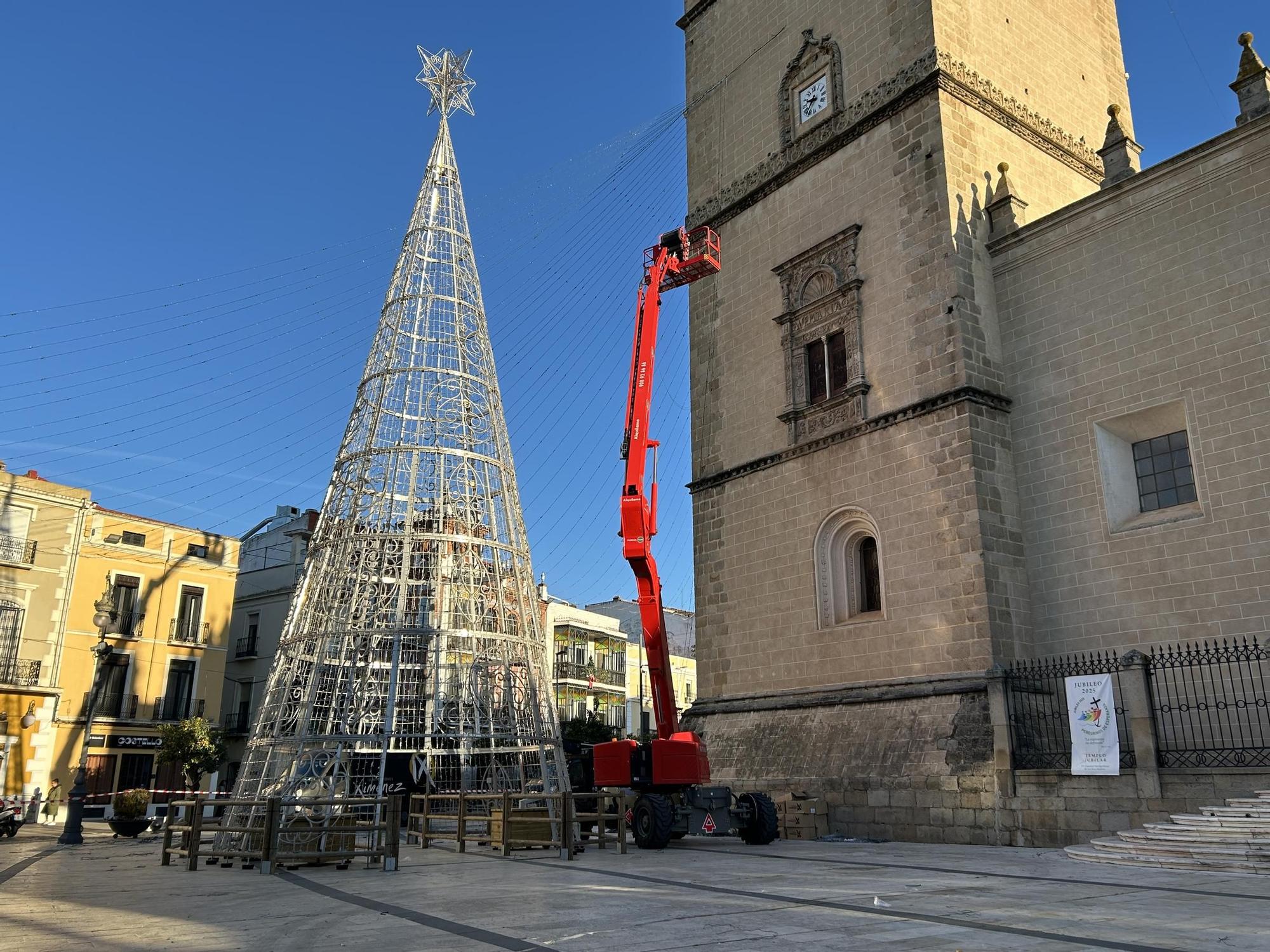 El árbol ya colocado en la plaza de España de Badajoz, mientras siguen instalando las tiras de luces.