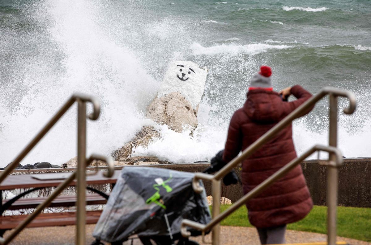 Un persona fotografiando las olas que chocan contra el malecón de Ballygally, en Irlanda del Norte.