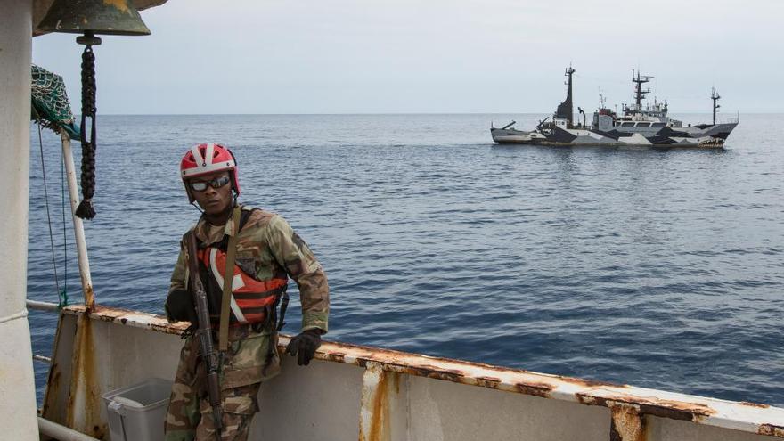 Un oficial liberiano a bordo del barco y la patrullera, al fondo.