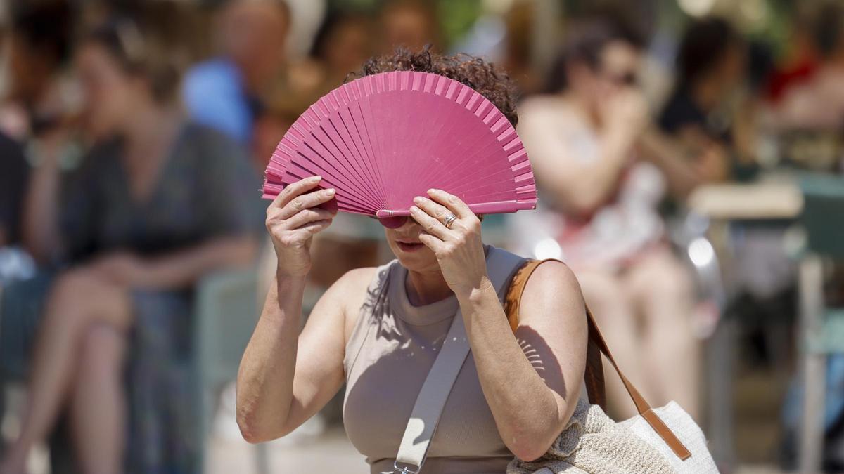 Una mujer se protege del sol con su abanico en plena ola de calor.