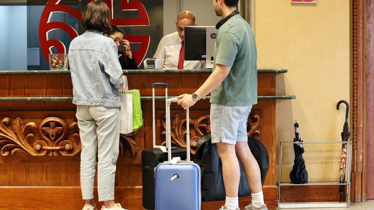 Unos clientes se registran a su llegada a la recepción de un hotel en Vigo.