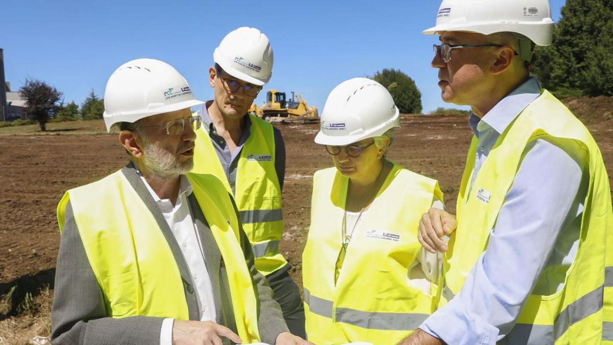 Por la izquierda, Jesús Menéndez, Óscar Veiras, Ana González y Pablo Fernández, ayer, en la zona de ampliación del hospital. A la izquierda, los primeros movimientos de tierra para adecentar la finca, con uno de los laterales del actual hospital al fondo. |  Marcos León 