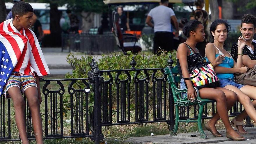 Adolescentes cubanos, uno de ellos envuelto en la bandera de EE UU, ayer, en un parque de La Habana.