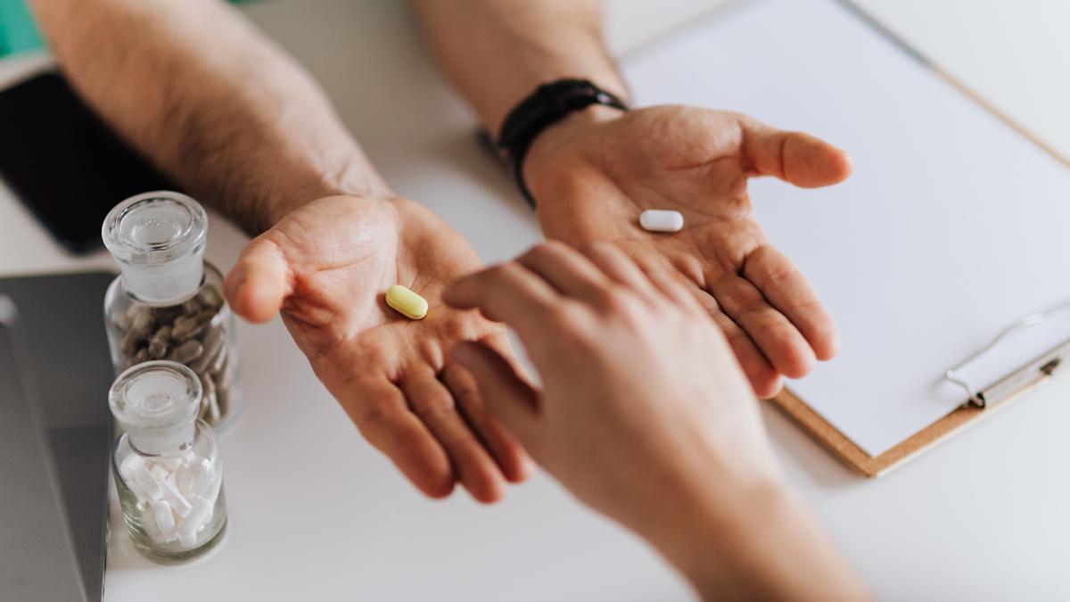 Un doctor ofrece dos pastillas diferentes a un paciente