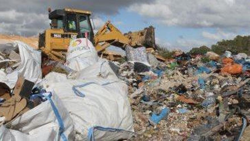 Una máquina esparce las bolsas de basura en el vertedero.