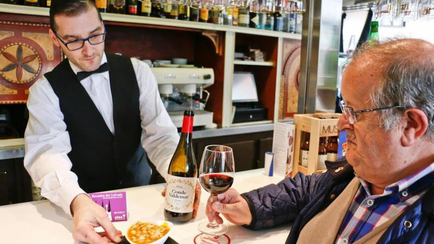 Un camarero sirve el bocado y el vino a un cliente.