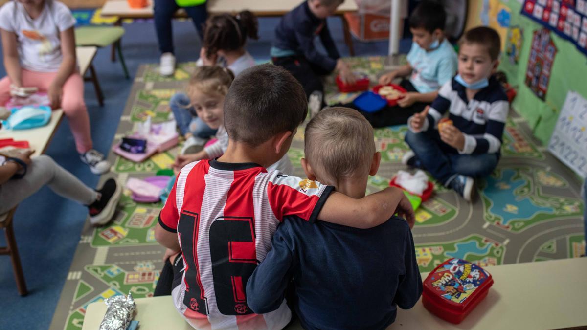 Un niño vestido con la equipación del Zamora CF le da un abrazo a uno de los niños ucranianos durante la hora del almuerzo en el colegio Nuestra Señora de La Paz de Villaralbo.