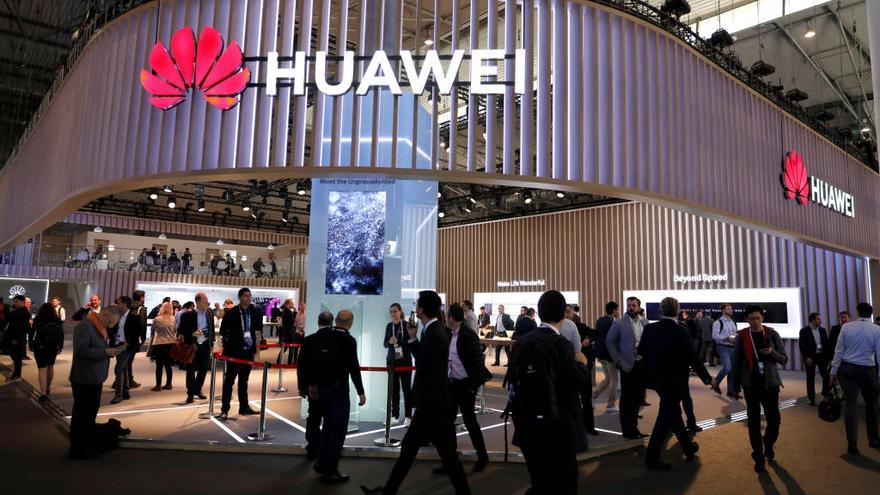 Los visitantes pasean junto a un expositor de Huawei en el MWC.