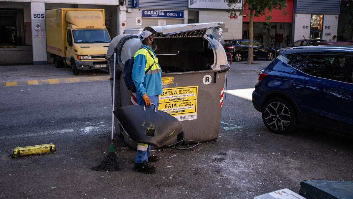 Un trabajador de la limpieza observa un contenedor de basura, en Badalona.