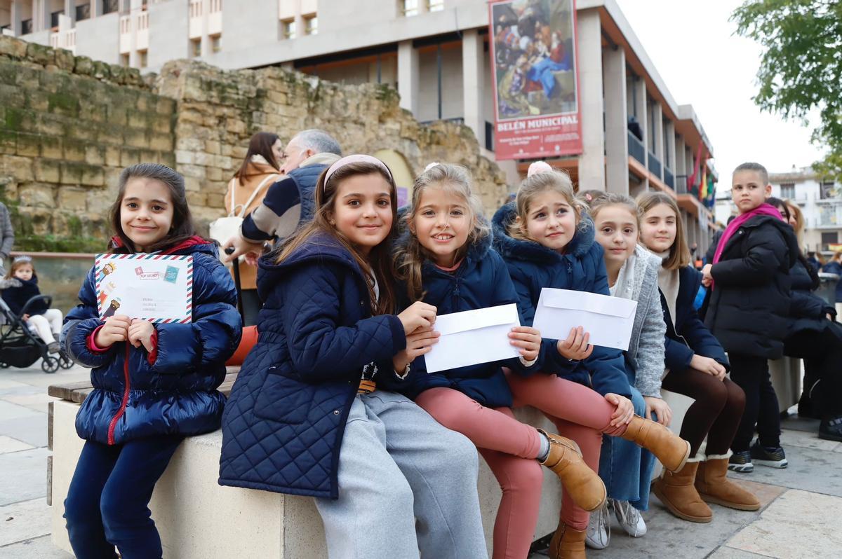 Un grupo de niñas esperan la salida del cartero real para entregarle su carta.