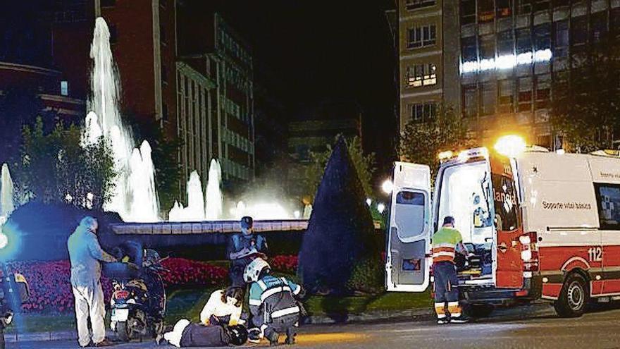 La mujer, tendida sobre el asfalto, atendida por los sanitarios.