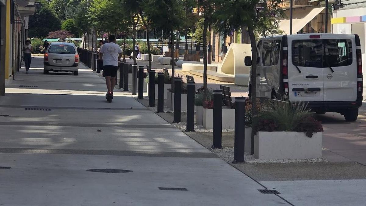 Un turismo, un patinete y una furgoneta transitando por la calle peatonal de Clara Campoamor.