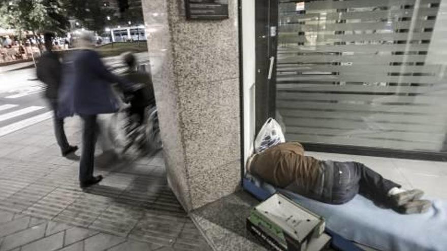 Un hombre duerme a las puertas de un cajero automático en la ciudad de Alicante.