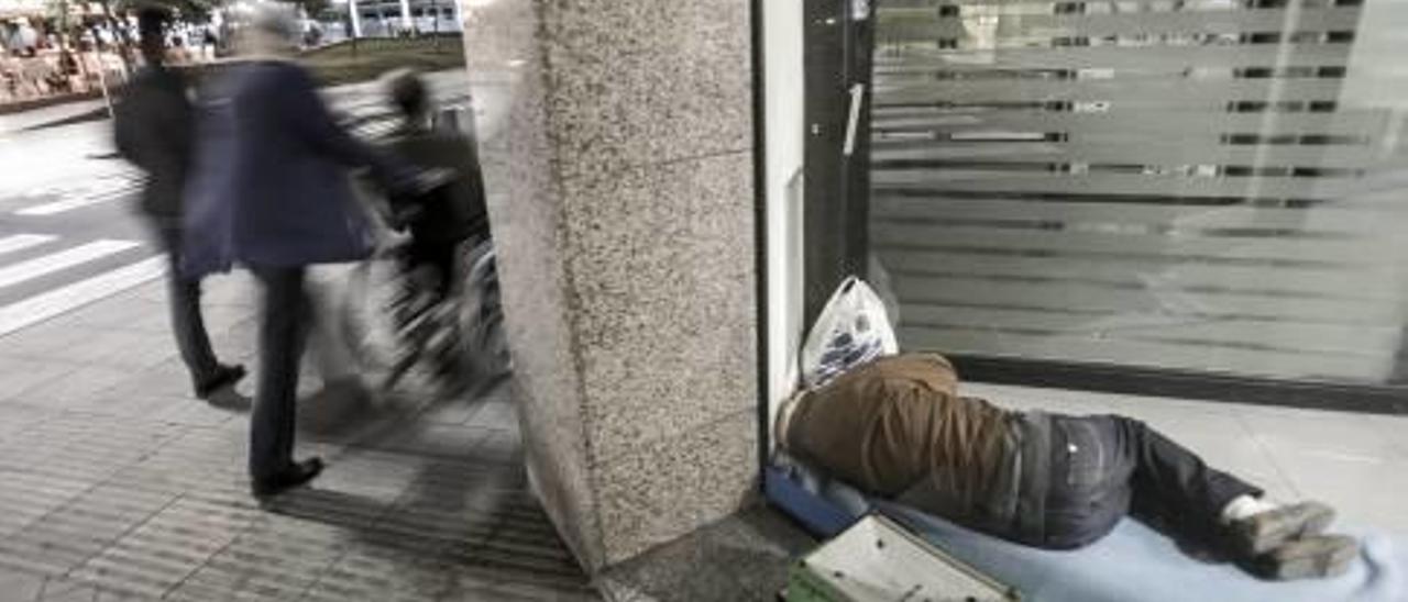 Un hombre duerme a las puertas de un cajero automático en la ciudad de Alicante.