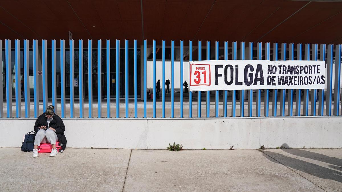 Una mujer al lado de un cartel de la huelga de transporte, tras una concentración por la huelga del transporte de viajeros, en la estación de autobuses de Santiago este viernes