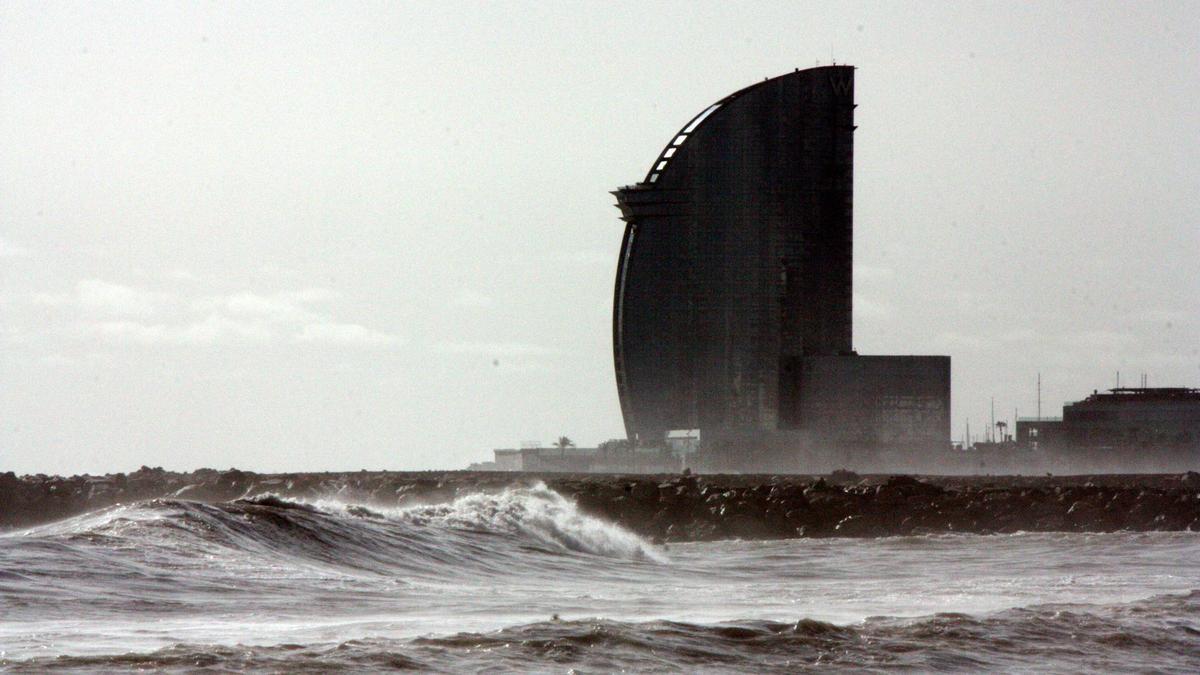 Primer pla de les onades a la platja de la Barceloneta amb l'Hotel Vela al darrera, en una imatge d'arxiu