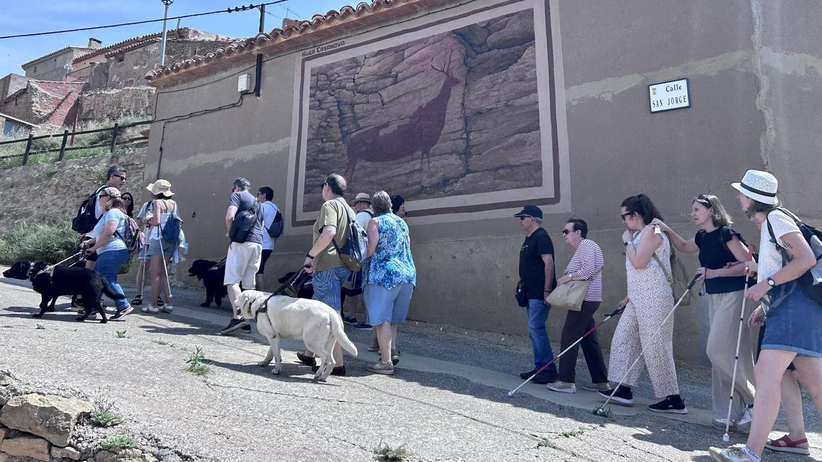 Usuarios de perros guía y voluntarios de CaixaBank durante la visita a las pinturas murales de arte rupestre de Alacón (Teruel).