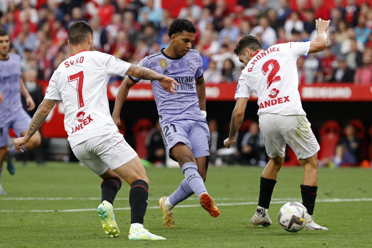 SEVILLA, 27/05/2023.- El delantero brasileño del Real Madrid Rodrygo Goes (c) marca su segundo gol entre Jesús Fernández Suso (i) y Gonzalo Montiel, del Sevilla, durante el partido de la jornada 37 de LaLiga disputado este sábado en el estadio Sánchez Pizjuán. EFE/Julio Muñoz