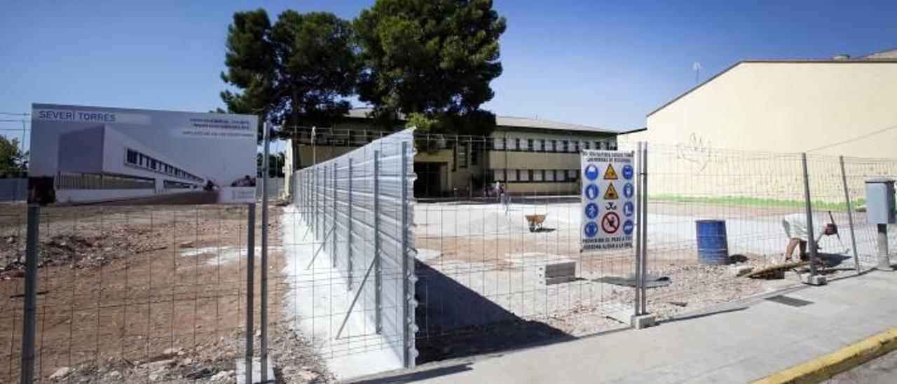 Obras en la parcela del colegio y, al otro lado de la valla, el cartel que anuncia el nuevo centro, ayer.