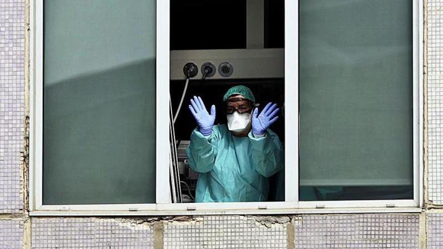 Una médica saluda desde la ventana de un hospital.