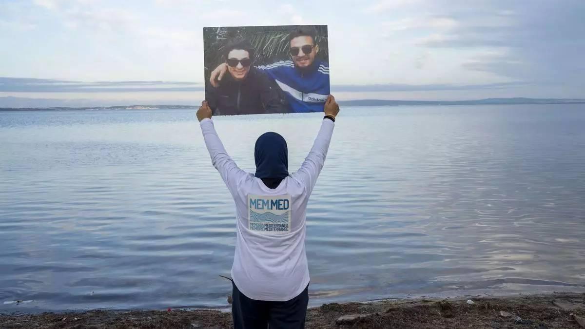 Una dona mostra un cartell amb dos familiars desapareguts al Mediterrani