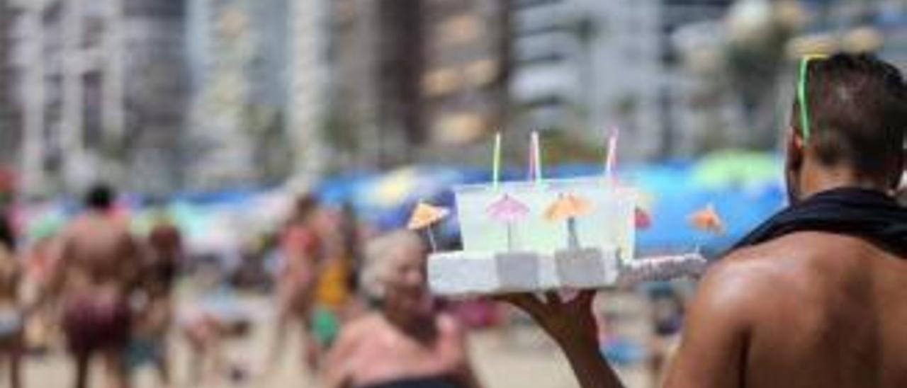 Un «mojitero» con la bandeja llena de cócteles, a la busca de clientes en una playa de Benidorm.