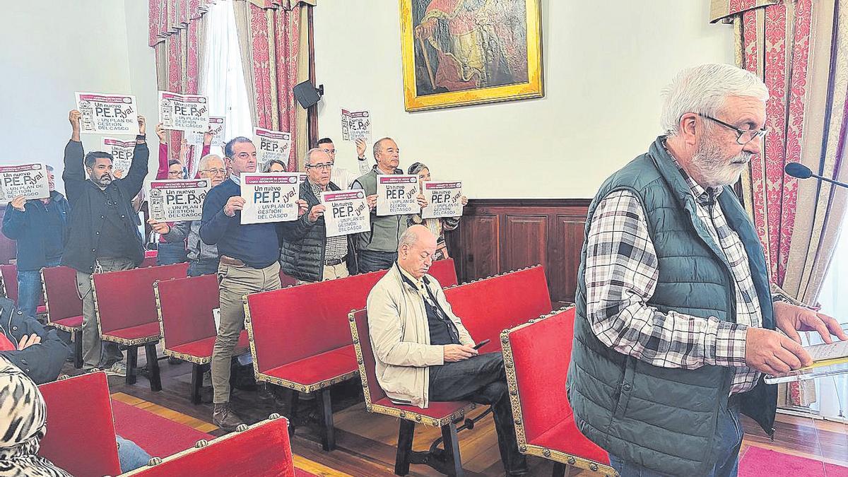 Miembros del colectivo muestran carteles durante la intervención de Pablo Reyes, a la derecha.