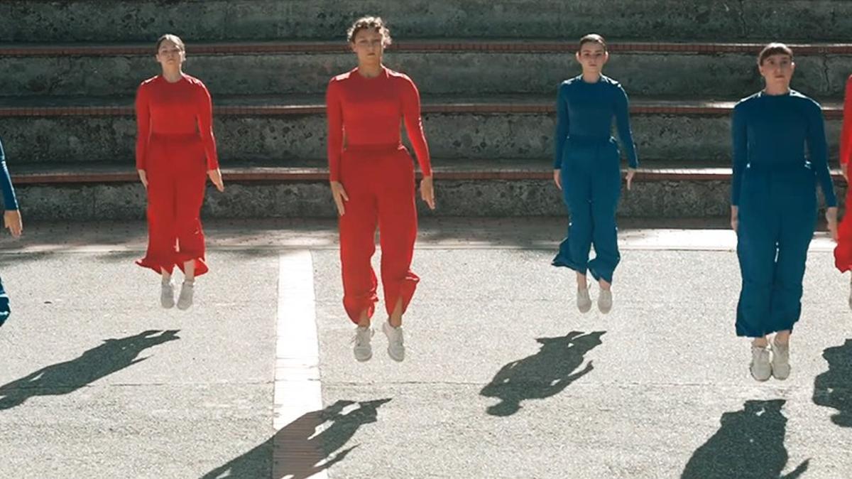 Sofia Papa (en primera fila, vestida de rojo) y su equipo de baile lucen atuendos monocromáticos para representar el movimiento de cargas positivas y negativas.
