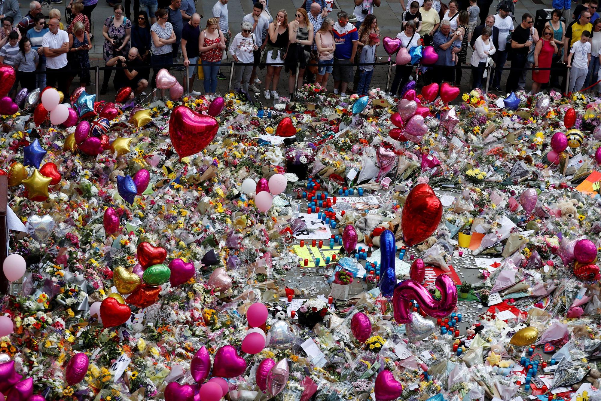 Espectadores del tributo floral por las víctimas del atentado en el Manchester Arena de 2017 unos días después de que ocurriera.