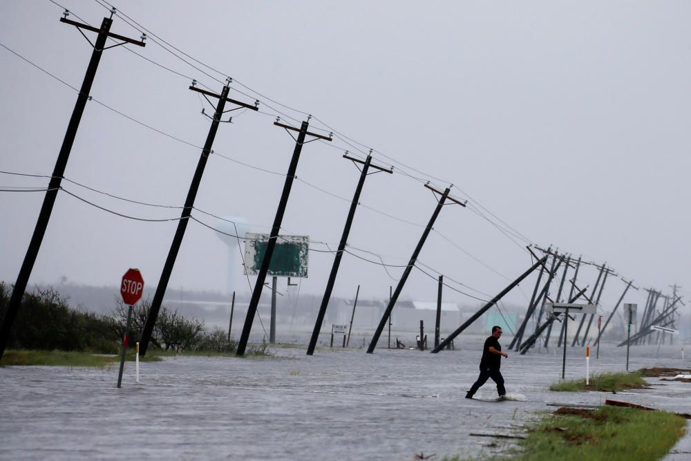 Un hombre camina a través de las inundaciones y sobre la carretera principal.