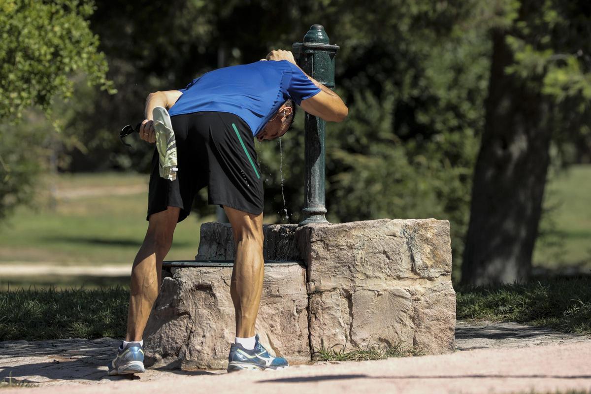 Un viandante combate el calor refrescándose en una fuente