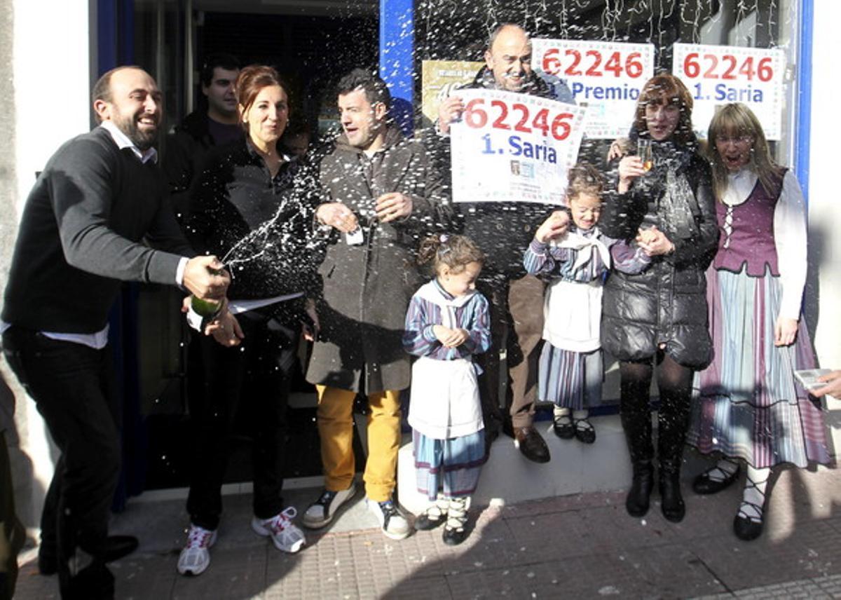 Premiats amb la Grossa de Nadal ho celebren amb xampany a l’entrada de l’establiment que ha venut 45 sèries del número 62.246.