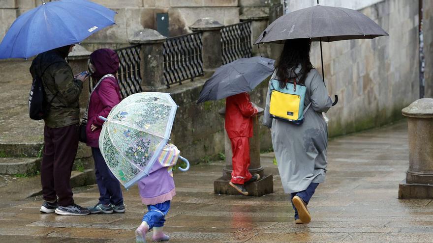 Nenos e adultos con paraugas camiñando pola zona vella de Santiago nun día de choiva no pasado mes de decembro.|  Antonio Hernández