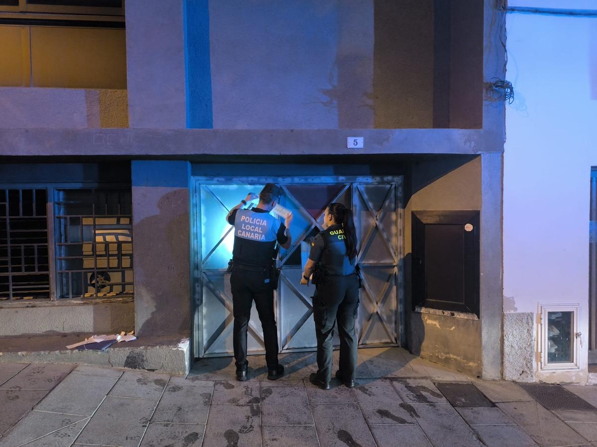 Agentes de la Policía Local y la Guardia Civil colocan el precinto en el local.