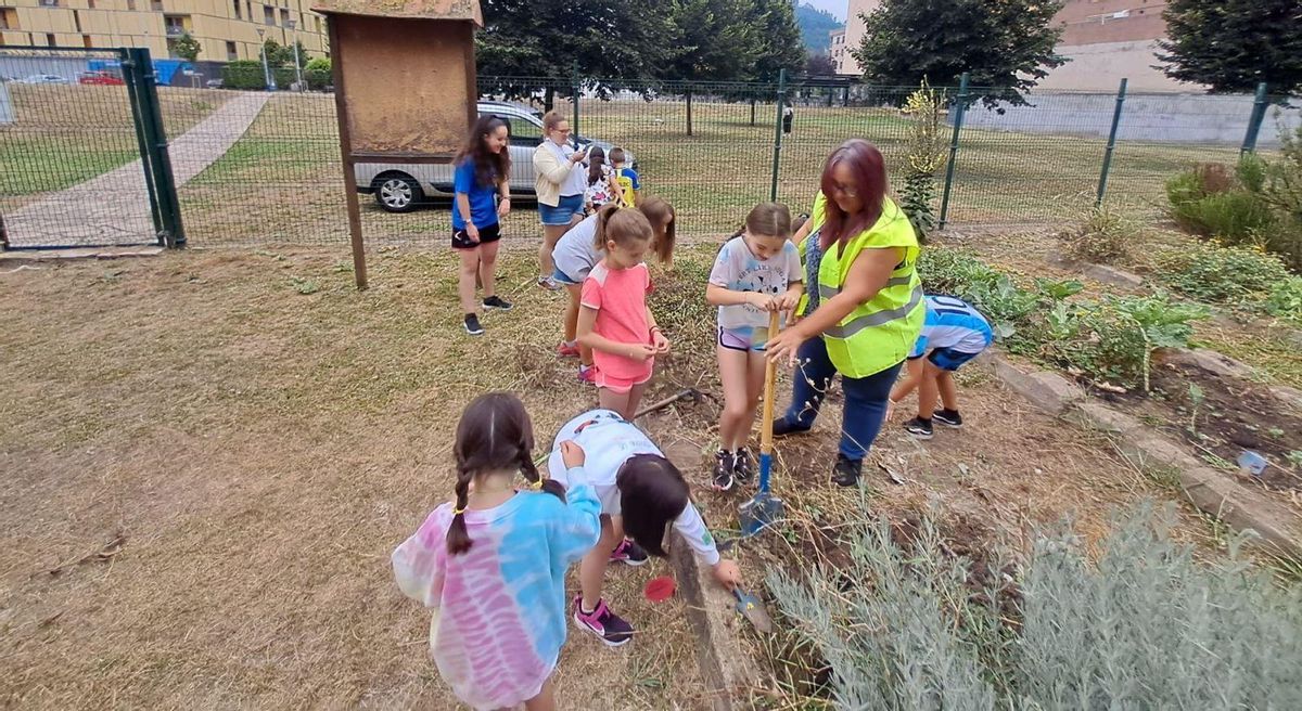 Un grupo de niños de primaria, ayer, aprendiendo a preparar la tierra en el ecohuerto de La Mayacina. | D. M.