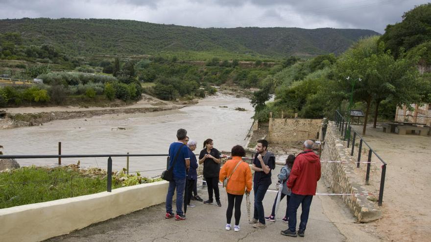 Varias personas observan la crecida del agua en Aielo de Malferit.