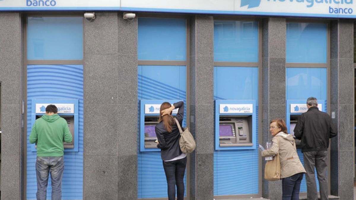 Varios usuarios en cajeros de una sucursal de Novagalicia Banco, en Santiago de Compostela.