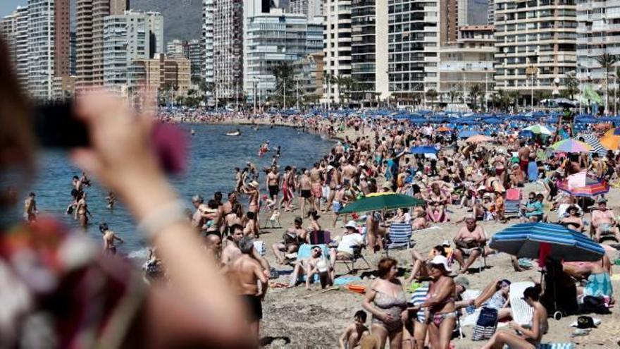 Una turista toma una fotografía de la playa de Levante de Benidorm hasta los topes, la pasada Semana Santa.