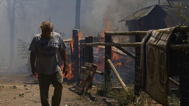 Un home passa pel costat d’un cobert en flames a prop del punt d’origen de l’incendi.  | DAVID APARICIO