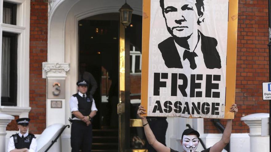 Un joven sujeta un cartel en apoyo a Assange frente a la embajada.